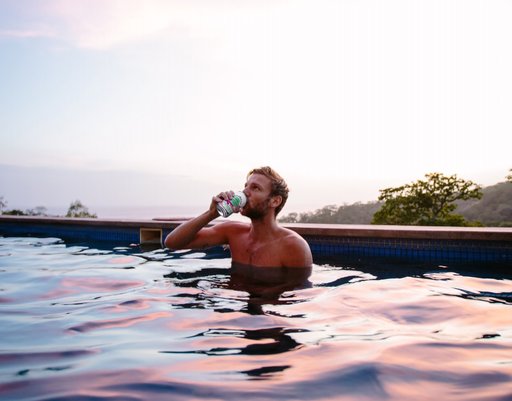 A man drinking a Soulboost in an outdoor pool.